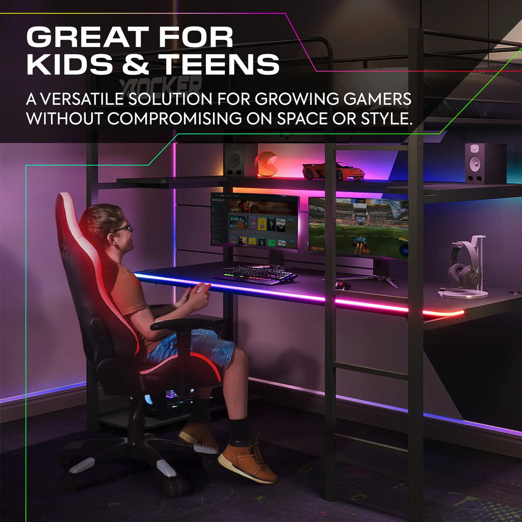 Person sitting at a gaming desk with multiple monitors and gaming equipment, surrounded by colorful lighting.