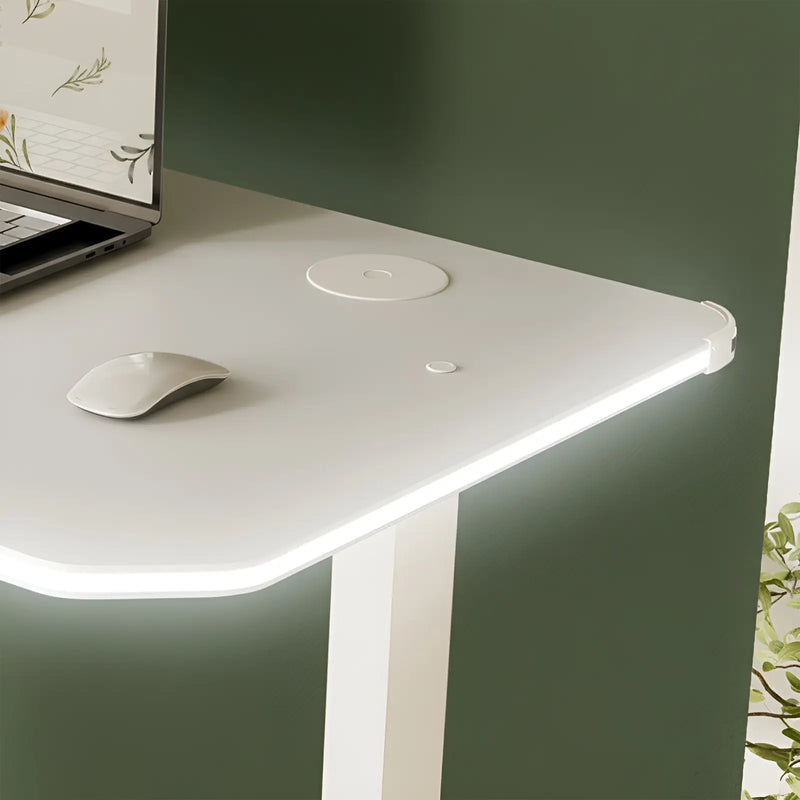 White desk with a laptop, mouse, and wireless charging pad on a green wall background