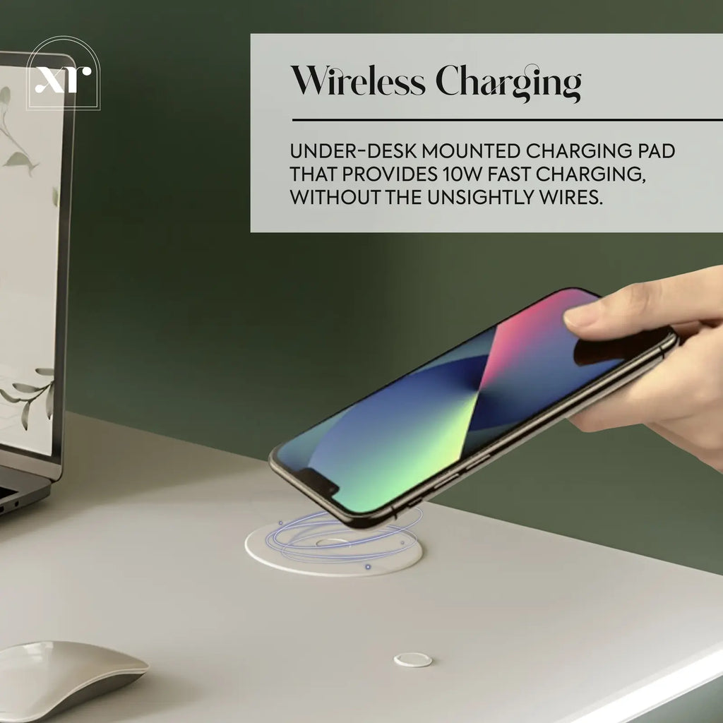Hand placing a smartphone on a wireless charging pad with text about the desk product's features.