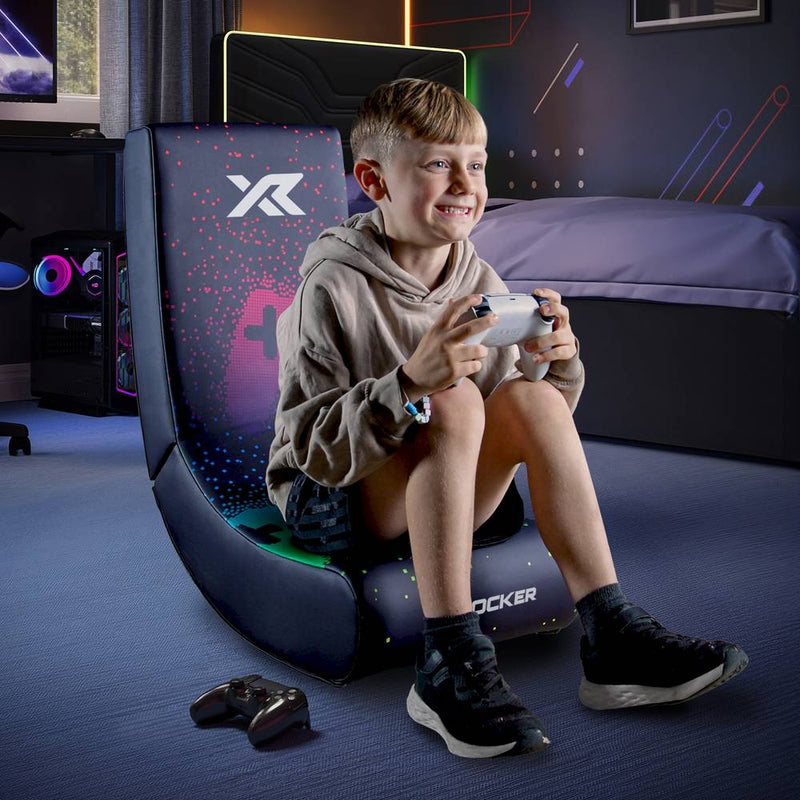 Child sitting on a gaming chair playing video games in a room with gaming equipment.