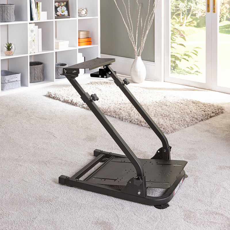 A black XR Racing racing rig wheel stand placed on a carpet in a living room setting, with adjustable parts for a racing simulation setup.
